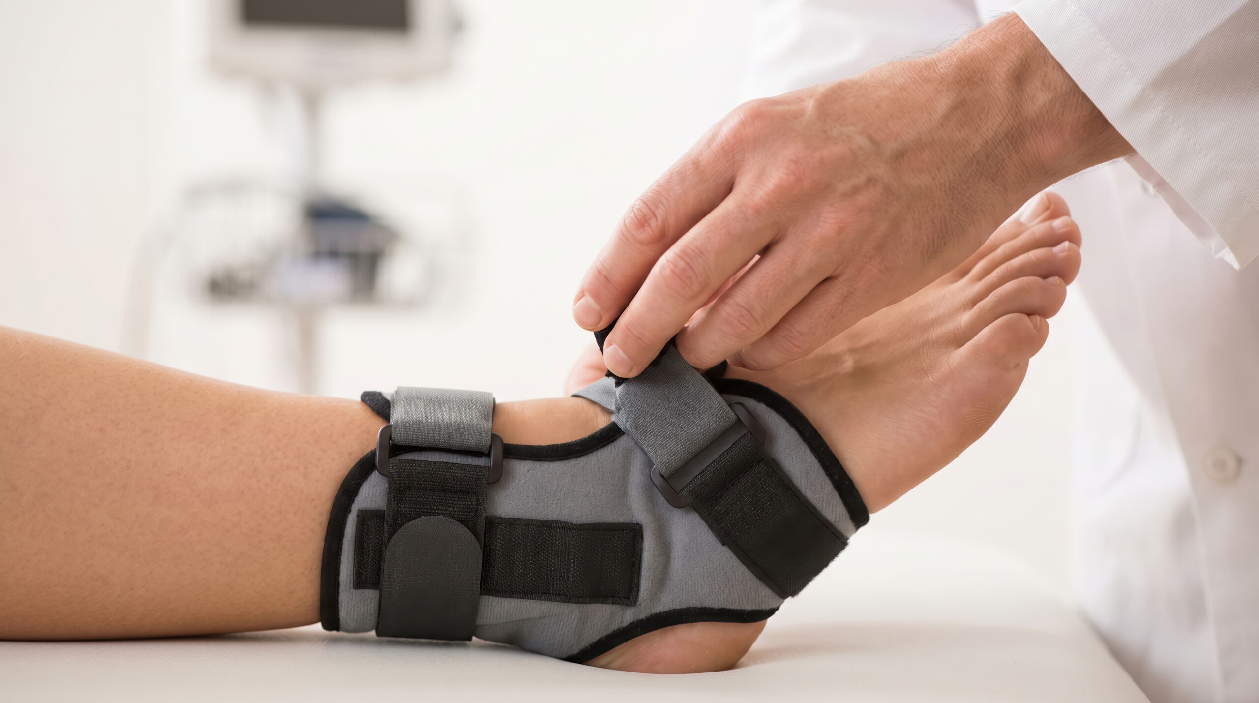 physical therapist tightening an ankle brace on his patient