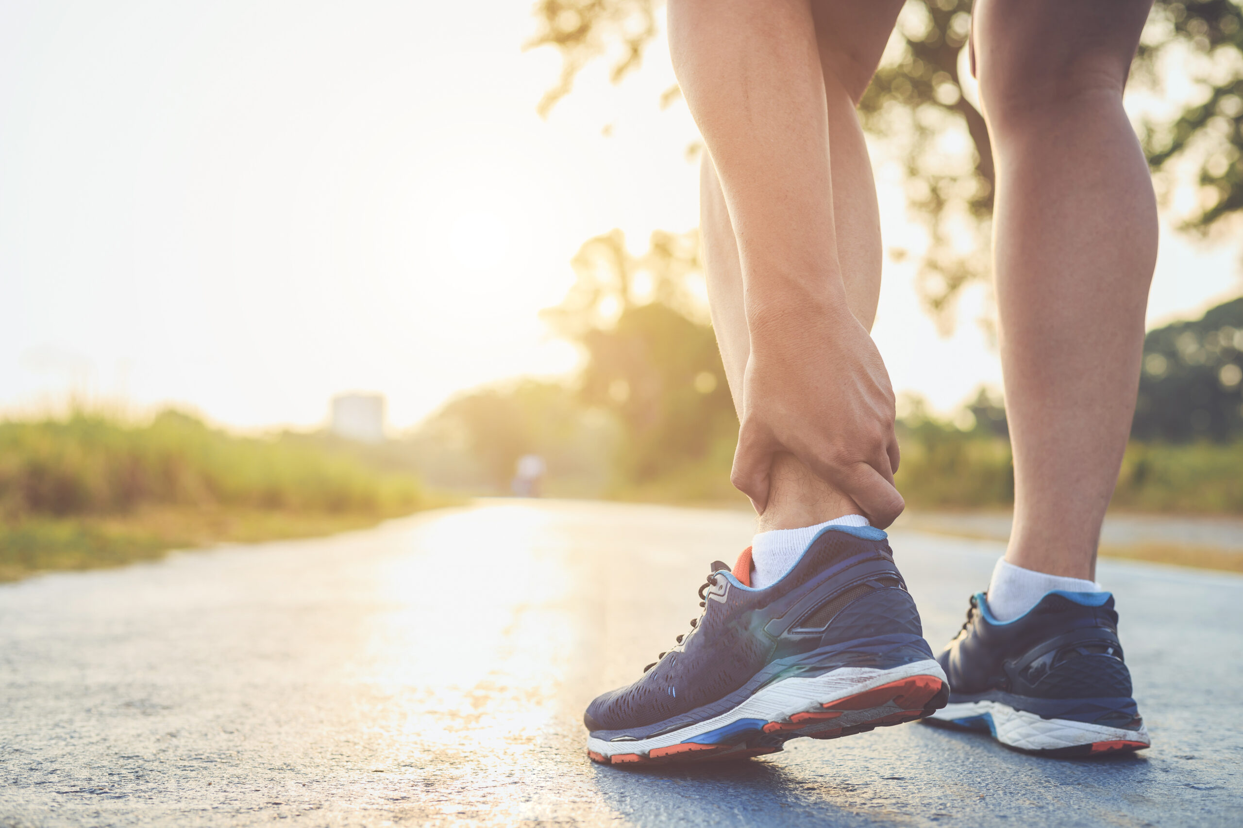person feeling ankle pain on their morning run